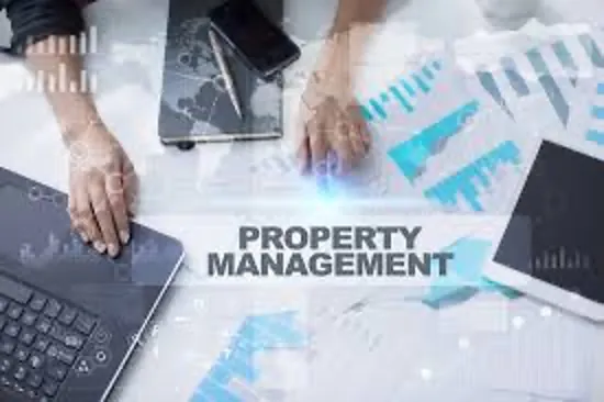 Hands working on a laptop and tablet with property management analytics